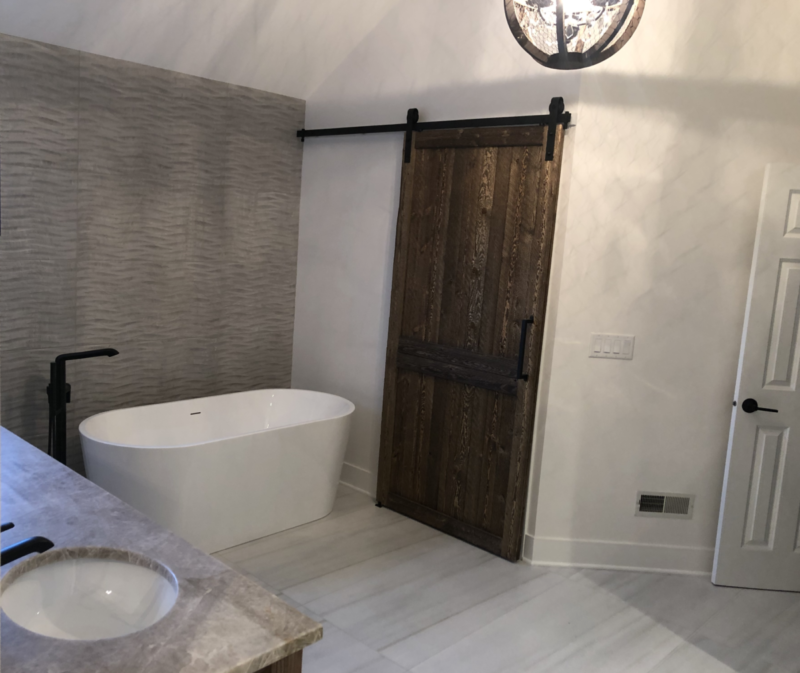 Modern Farmhouse-inspired Bathroom with Barn Door, Gray Flooring and Accent Wall